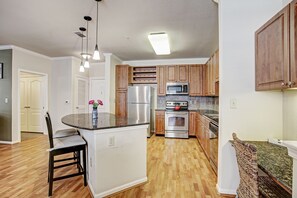 Stocked kitchen with granite countertops, electric cooktop, microwave & more