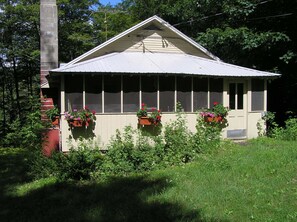 The screened porch of the cottage with flower boxes.