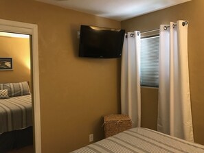 Master bedroom has a King-sized bed, TV and Apple chargers on nightstands
