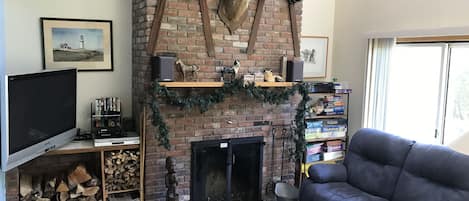 Living room with cathedral ceiling, wood-burning fireplace, and 50" TV