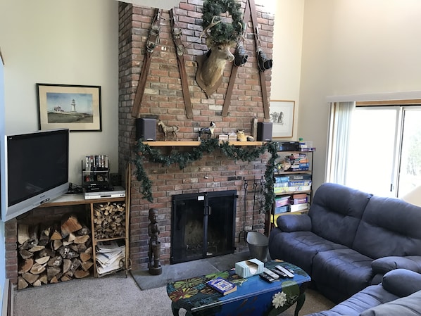 Living room with cathedral ceiling, wood-burning fireplace, and 50" TV