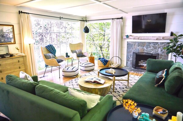 Light filled living room with walls of windows that look into the forest