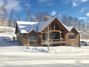 Back of lodge with view of upper patio with grill and fireplace.  