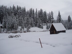 Snow covered meadow, with the Stanislaus River in the back, along the tree line.