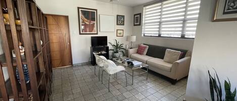 Living room with a 28 smart tv, wifi, air conditioning and a ceiling fan.