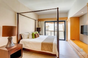 The master bedroom with a stylish king canopy bed, TV & balcony access