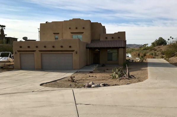 Front of home with large driveway down to boat dock and ramp.