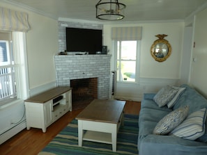 Living room with fireplace and TV.  Windows overlook marsh and ocean