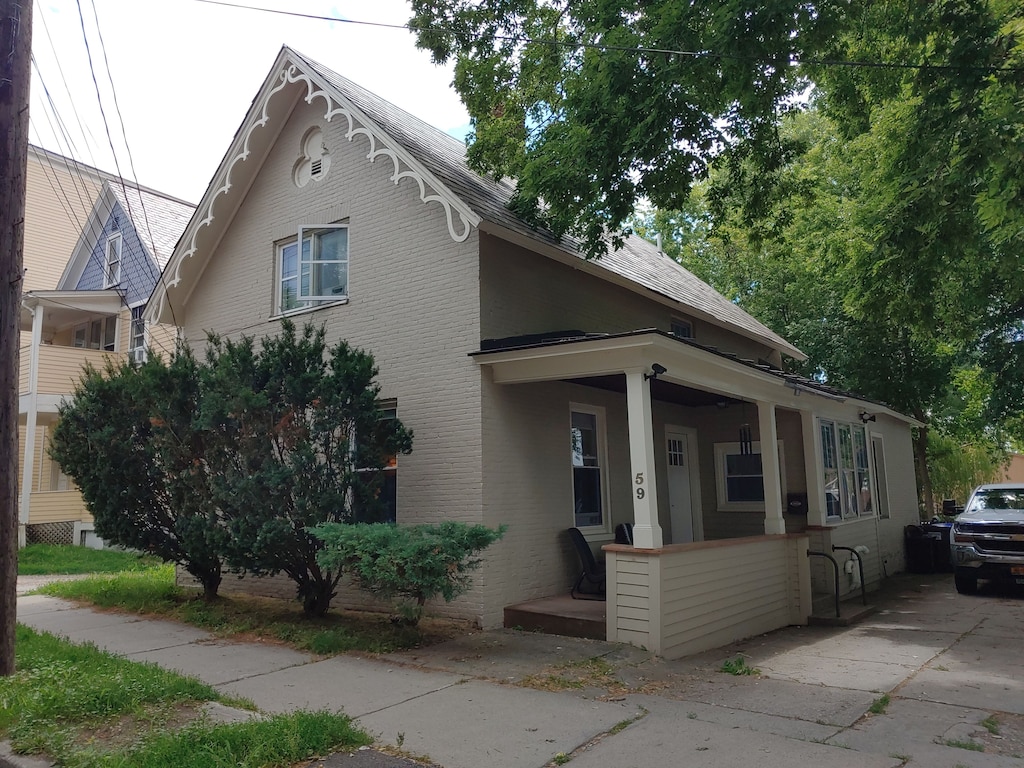 The front of a gray Burlington vacation rental with shrubbery in front, and large trees beside it.