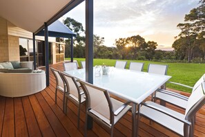 Dine alfresco with stunning valley views. The deck features a comfortable seating area and a BBQ, perfect for relaxed outdoor meals.