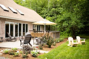 Road side view of grounds and wood deck, seating for 12 adjacent the kitchen