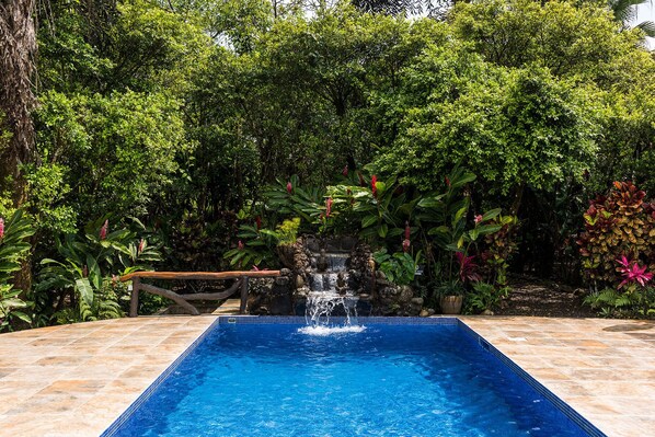 Swimming pool with waterfall and patio furniture.  Refreshing and invigorating.