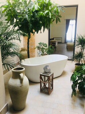 Private interior patio featuring stylish bathtub surrounded by local plants 