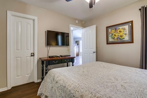 Downstairs bedroom with queen size bed, TV, and ceiling fan