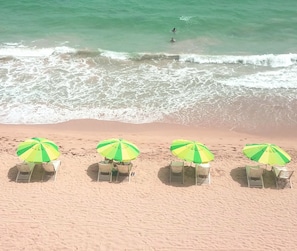 Beach chairs and umbrellas for rent out front on Condado Beach
