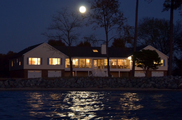 SuperMoon rising behind the house with moon beams on the bay