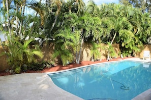 Pool deck is surrounded by six foot privacy fence and lush foiliage.