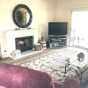 Living room with golf course and mountain view, fire place, and flat screen TV.