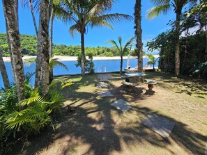 Mesa de pedra e jardim descoberto em frente à praia - acesso ao píer.