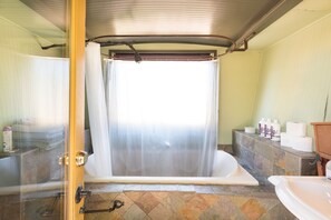 Entering your private bathroom with garden tub and stone tile. Sunset deck above