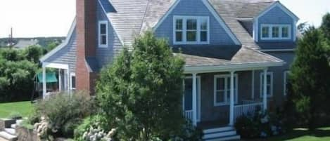 Front view. The backyard has a swingset and shed with an outdoor shower