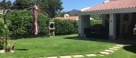 Sunny front garden with barbecue and  a large parasol