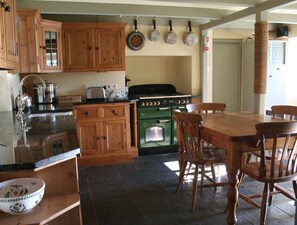Cottage-style kitchen with range oven, flagstone slate floor and dining area.