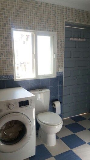 Bathroom with shower, washing machine, fire extinguisher and first aid kit