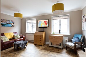 Open plan sitting room showing sofa bed and table with 4 chairs inside