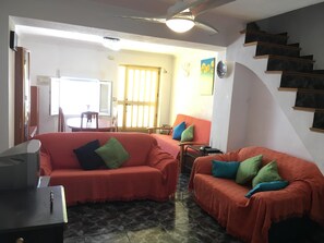 Living room area has two sofas, tv and stairs to the first floor