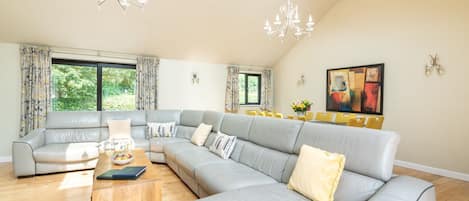 Open plan living area with 10 seater sofa and 10 seater dining table. 