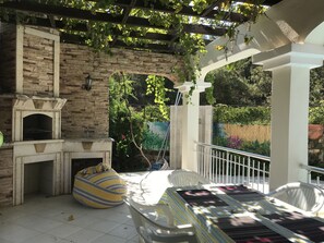 BBQ and terrace overlooking pool under grape vines.