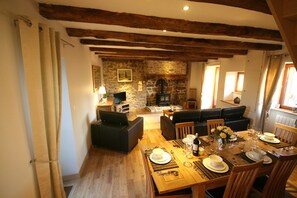Open plan lounge and dining area with TV and wood burning stove