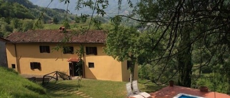 view of pool and house from the hillside