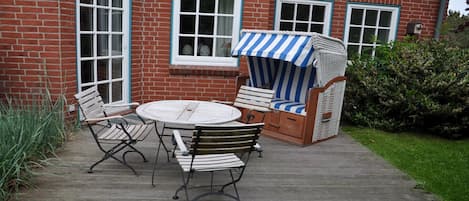 Die großzügige Terrasse mit Strandkorb, Teak Tisch und Stühlen und Grill