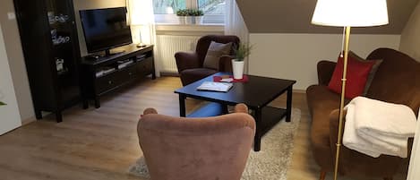 Wohnzimmer mit Sitzecke, Flatsreen und Regal mit Gläsern und Büchern