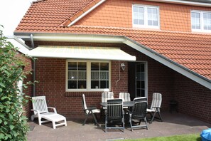 Die Terrasse mit Markise, Liege und Gartenmöbeln