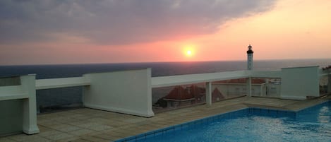 Coucher de soleil sur le phare,  vue du toit de la résidence depuis la piscine