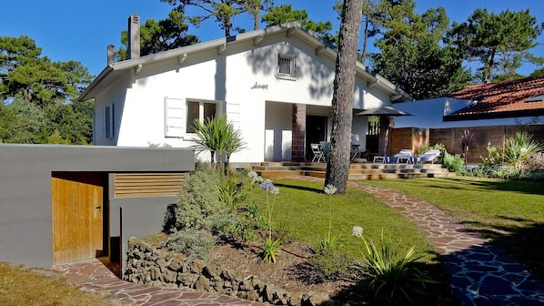 Vue du jardin avec le  garage et la douche extérieure, sur la gauche
