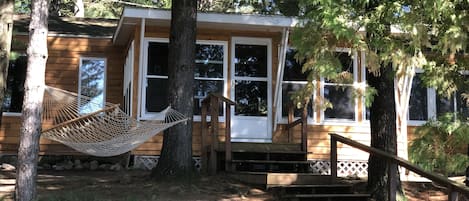 New cedar siding this year (2022), view from the patio up to the cottage porch. 