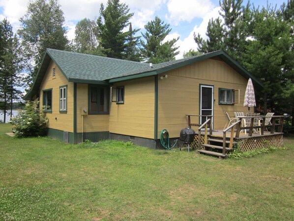 Cabin with attached deck, overlooking water. 