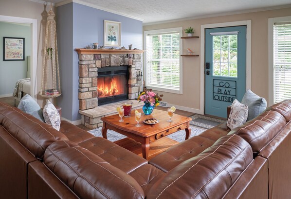 Living room with leather sectional sofa, wood-burning fireplace and streaming tv