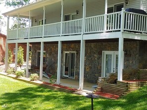 Lakeside view of upper porch has a gas grill and lower porch has a porch swing