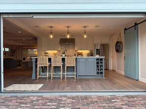 Entire kitchen wall of windows opens to bring the outside inside.