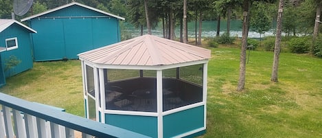 A look off the back porch at the 8-chair screened gazebo and  yard to the river