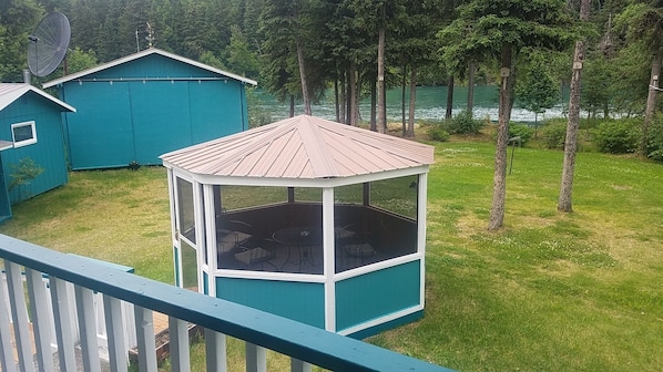 A look off the back porch at the 8-chair screened gazebo and  yard to the river