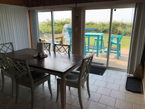 Sunroom with table and six chairs with dune and water views.
