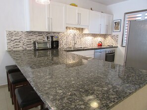 Large kitchen with granite counters, rock backsplash, and stainless appliances

