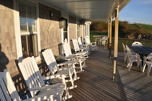 Large deck with rocking chairs overlooks yard and has ocean views