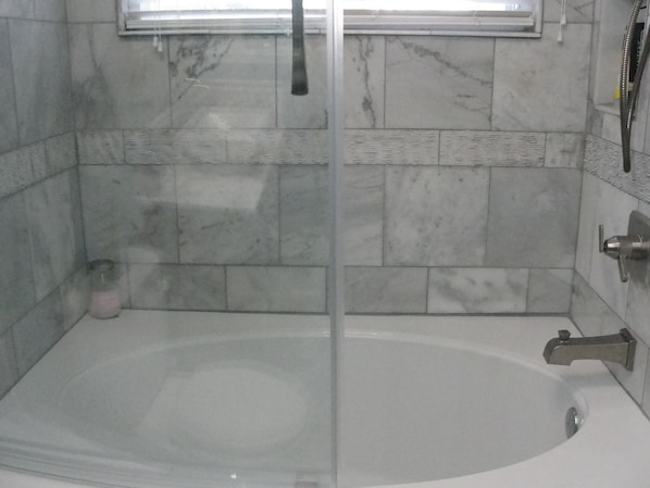 Nice inviting marble surround shower/tub with dual shower heads.
